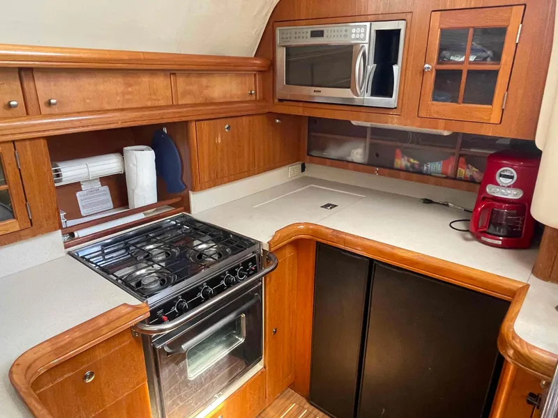 Slide: The Image of 2006 Hunter 45 Center Cockpit kitchen with stove, microwave, and wooden cabinetry. - 25