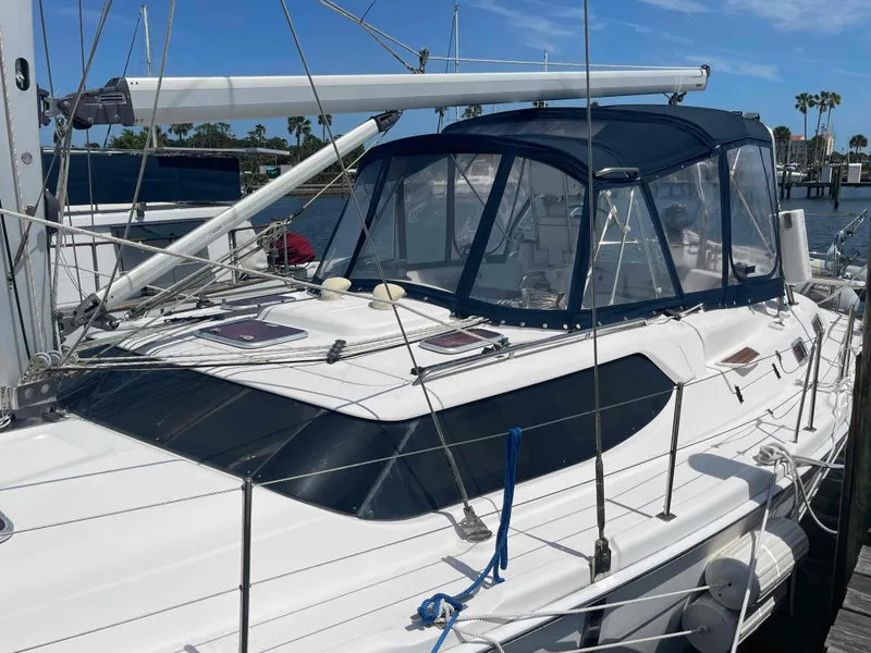 Slide: The Image of 2006 Hunter 45 Center Cockpit sailboat docked, featuring a sleek design and blue canopy. - 48