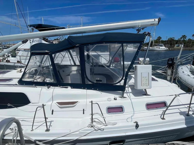 Slide: The Image of 2006 Hunter 45 Center Cockpit sailboat docked, featuring a blue canopy and sleek design. - 49