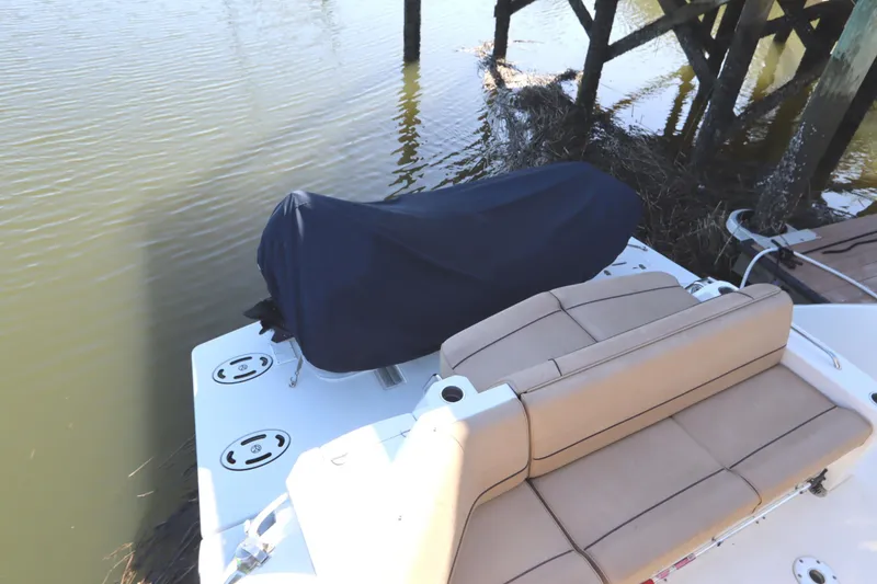 Slide: The Image of 2015 Cruisers Cantius boat with covered equipment and tan seating by the water. - 16