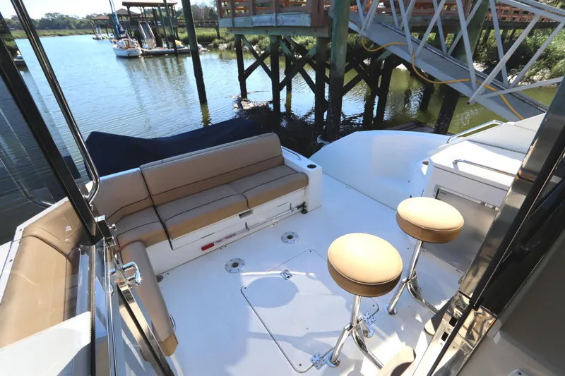 Slide: The Image of 2015 Cruisers Cantius yacht deck with seating and stools by the water. - 32