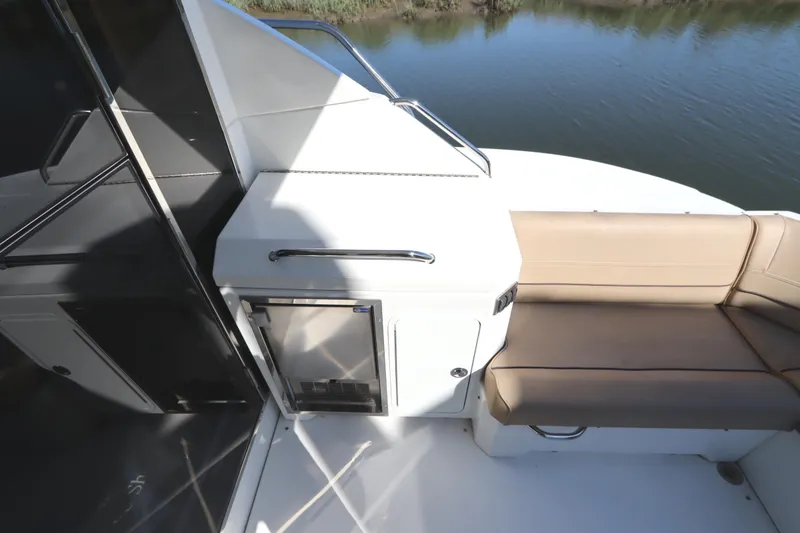 Slide: The Image of 2015 Cruisers Cantius boat deck with seating and storage, overlooking calm water. - 9