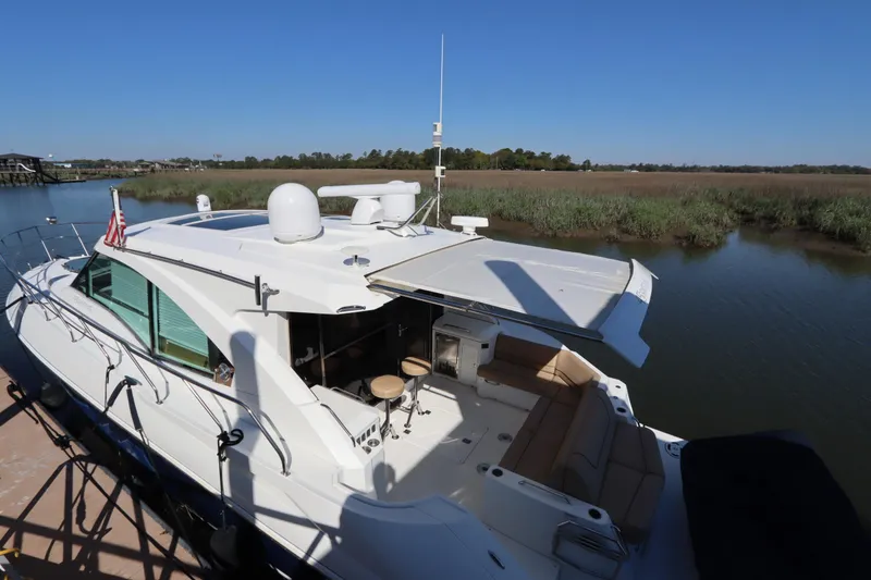Slide: The Image of 2015 Cruisers Cantius yacht docked by a serene riverbank under clear blue skies. - 3
