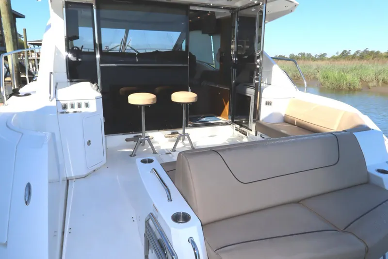 Slide: The Image of 2015 Cruisers Cantius yacht interior with seating and bar stools, docked by a scenic waterway. - 5