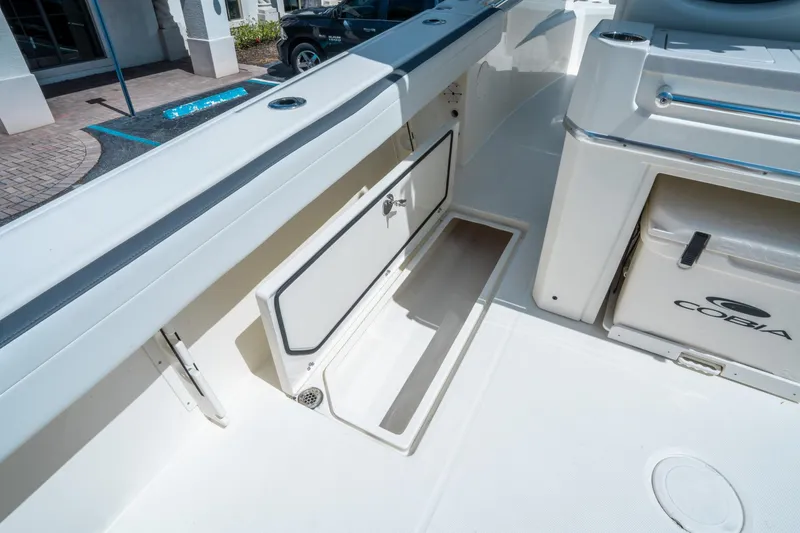 Slide: The Image of 2025 Cobia 285 CC boat interior with open storage compartment and cooler. - 16