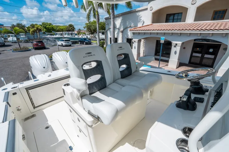 Slide: The Image of 2025 Cobia 285 CC boat interior with dual seats and steering wheel, parked outdoors. - 24
