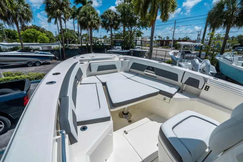 Slide: The Image of 2025 Cobia 285 CC boat interior with seating and table, surrounded by palm trees. - 29