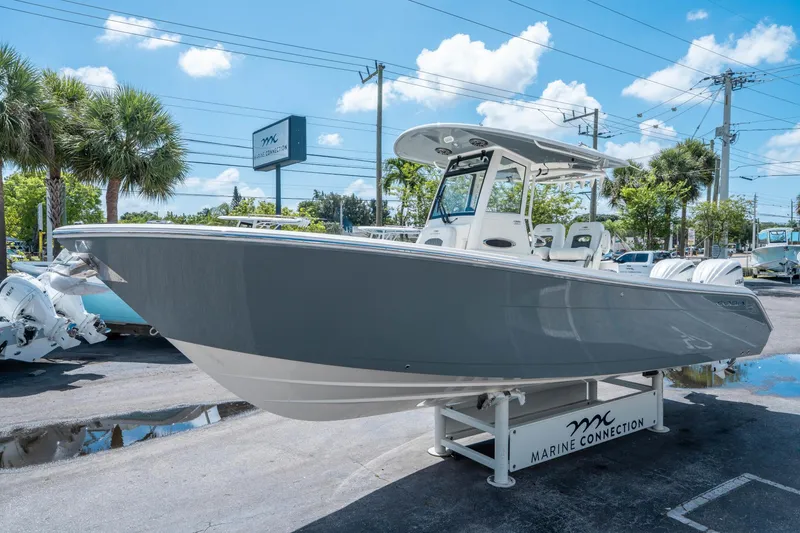 Slide: The Image of 2025 Cobia 285 CC boat displayed at Marine Connection dealership under clear blue sky. - 6