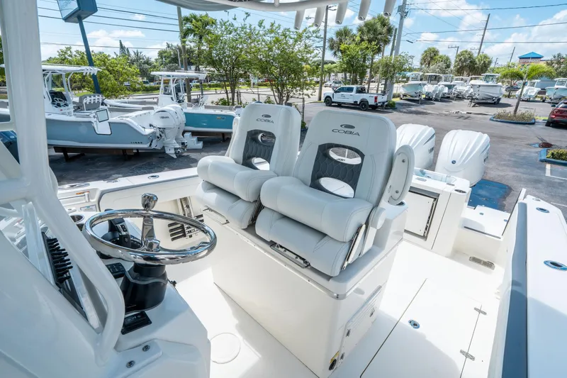 Slide: The Image of 2025 Cobia 285 CC boat interior with dual helm seats and steering wheel. - 22
