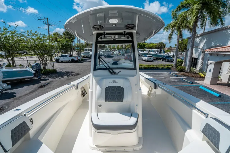 Slide: The Image of 2025 Cobia 285 CC boat, sleek design, parked outdoors under clear blue sky. - 31