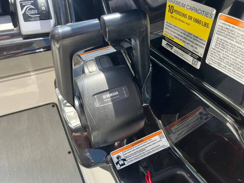 Slide: The Image of Throttle control of 2022 Yamaha Boats AR210, showing capacity and safety labels. - 16