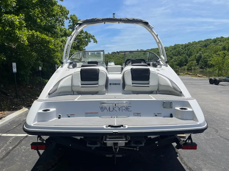 Slide: The Image of 2022 Yamaha AR210 boat, rear view, parked on a sunny day near lush greenery. - 4