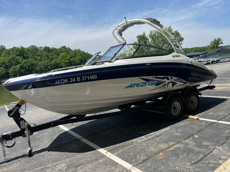 Slide: The Image of 2022 Yamaha AR210 boat on trailer in parking lot, surrounded by trees. - 7