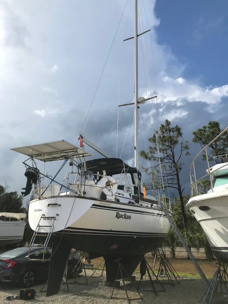 Slide: The Image of 1990 Endeavour 38 CC sailboat on dry dock, with overcast sky and surrounding trees. - 13