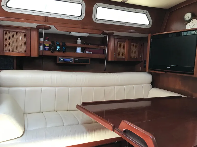 Slide: The Image of Interior of 1990 Endeavour 38 CC yacht with white seating and wooden table. - 4