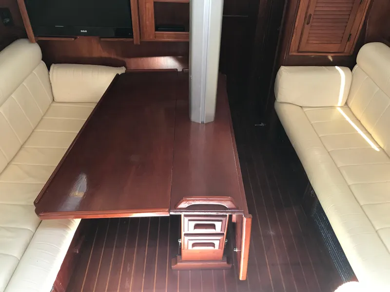 Slide: The Image of Interior of 1990 Endeavour 38 CC sailboat with wooden table and cream seating. - 6
