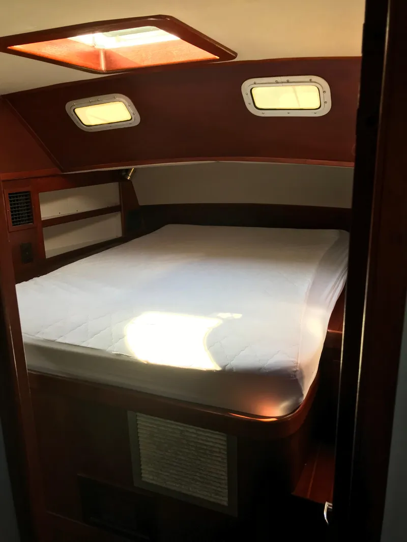 Slide: The Image of 1990 Endeavour 38 CC yacht cabin with bed, wooden interior, and portholes. - 7