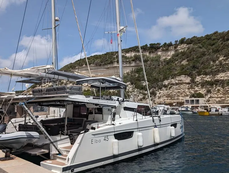 Slide: The Image of 2022 Fountaine Pajot Elba 45 catamaran docked in a scenic marina setting. - 5