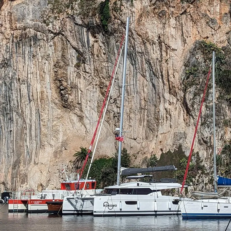 Slide: The Image of 2022 Fountaine Pajot Elba 45 catamaran docked near rocky cliffs. - 6