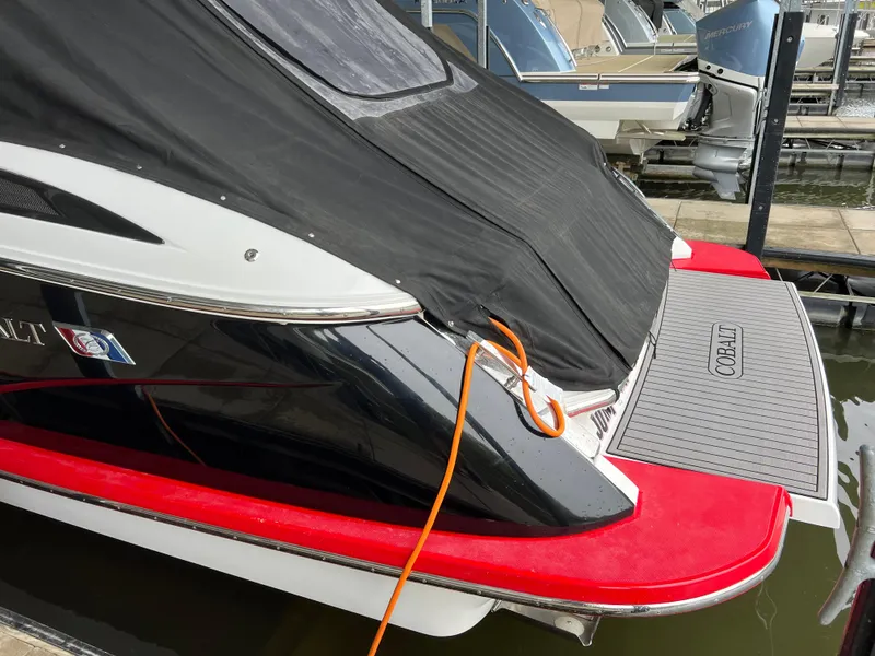 Slide: The Image of 2022 Cobalt A36BR boat with cover, docked, featuring red accents and orange rope. - 18
