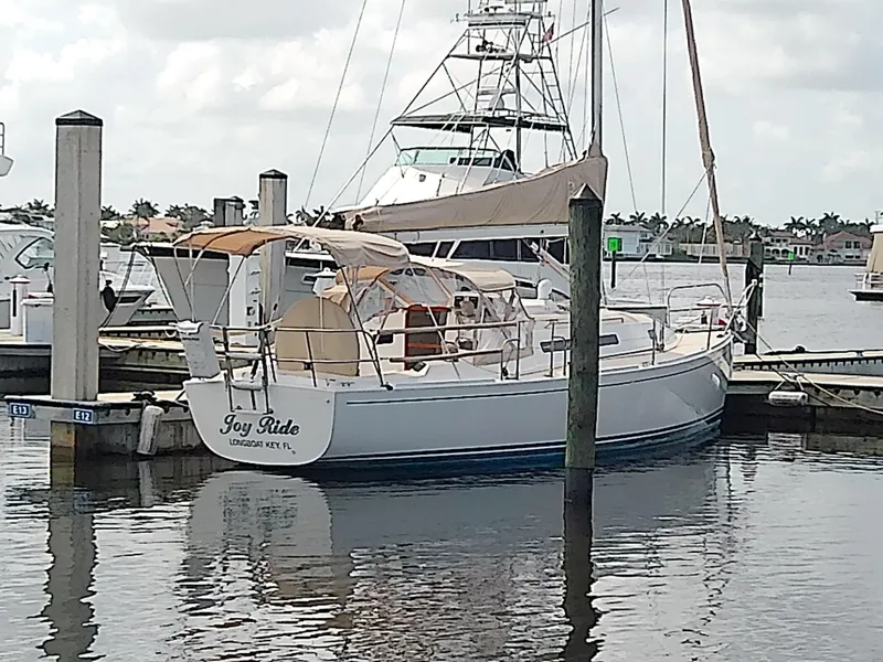 Slide: The Image of 2004 J Boats J/32 sailboat docked in a marina with waterfront buildings in the background. - 31