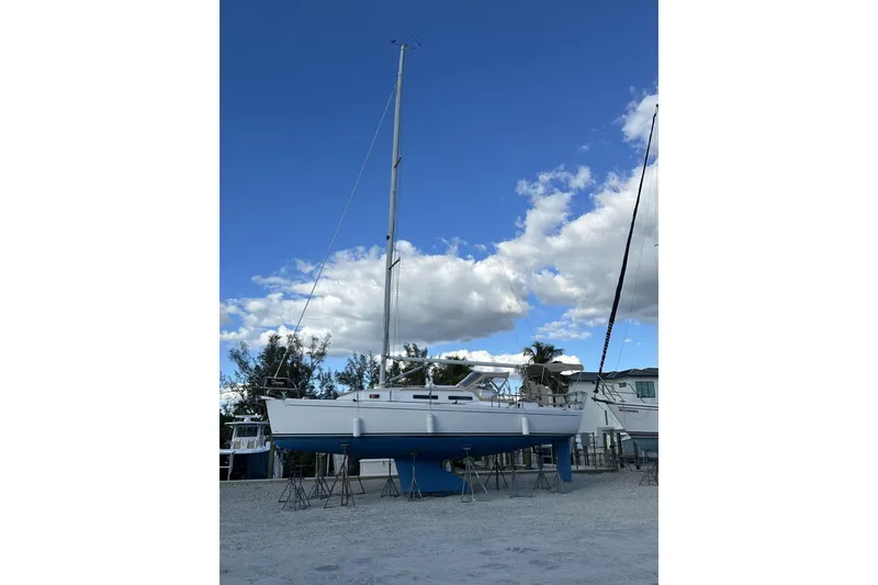 Slide: The Image of 2004 J Boats J/32 sailboat on stands, white hull, blue keel, cloudy sky background. - 86