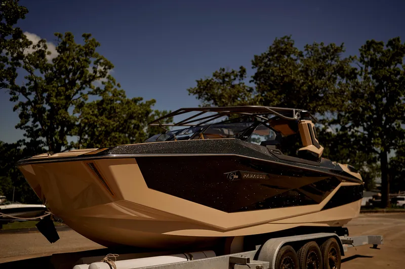 Slide: The Image of 2025 Nautique Super Air Nautique G25 Paragon boat on trailer, surrounded by trees. - 3