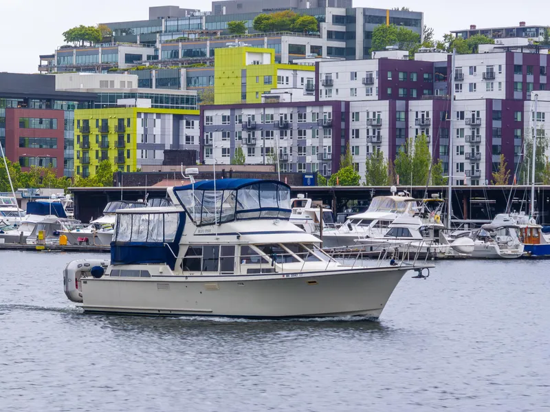 Slide: The Image of 1988 Tollycraft 44 CPMY yacht cruising in urban marina with colorful buildings in background. - 35