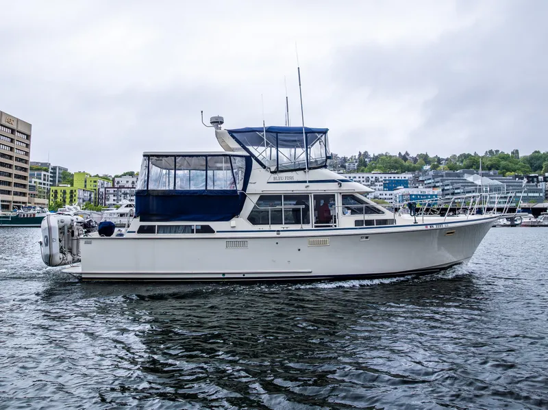 Slide: The Image of 1988 Tollycraft 44 CPMY yacht cruising on a calm waterway with cityscape background. - 5