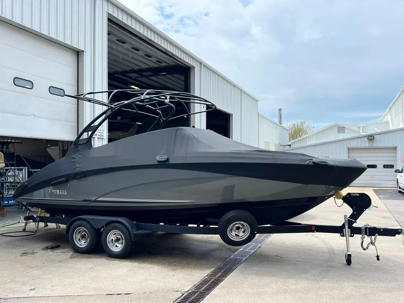 Slide: The Image of 2019 Yamaha Boats 242 Limited S covered on trailer outside a warehouse. - 14