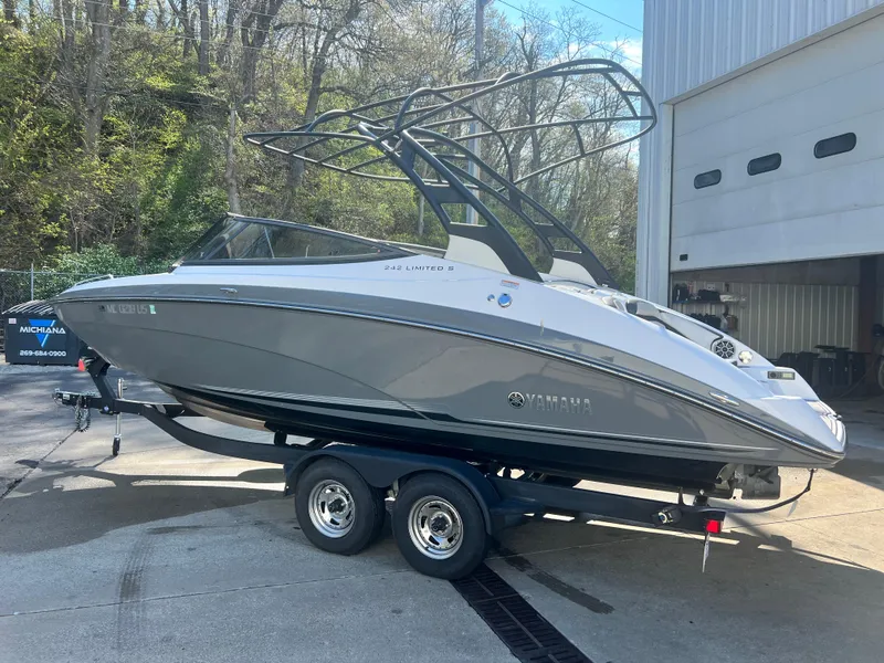 Slide: The Image of 2019 Yamaha Boats 242 Limited S on trailer, parked outdoors near a building. - 2