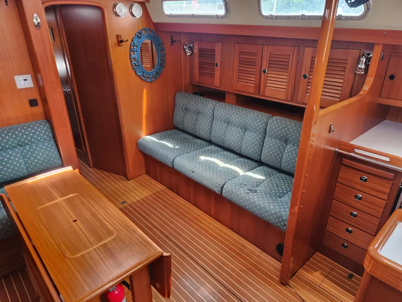 Slide: The Image of Interior of 2003 Hallberg-Rassy 46 yacht with wooden furnishings and blue cushioned seating. - 30