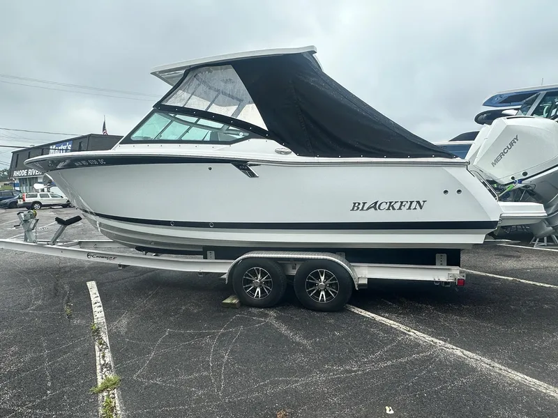 Slide: The Image of 2020 Blackfin 272 DC boat on trailer, parked in a lot, with black canopy. - 2