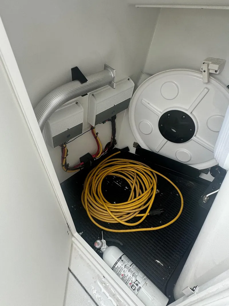 Slide: The Image of 2020 Blackfin 272 DC storage compartment with coiled hose and fire extinguisher. - 29