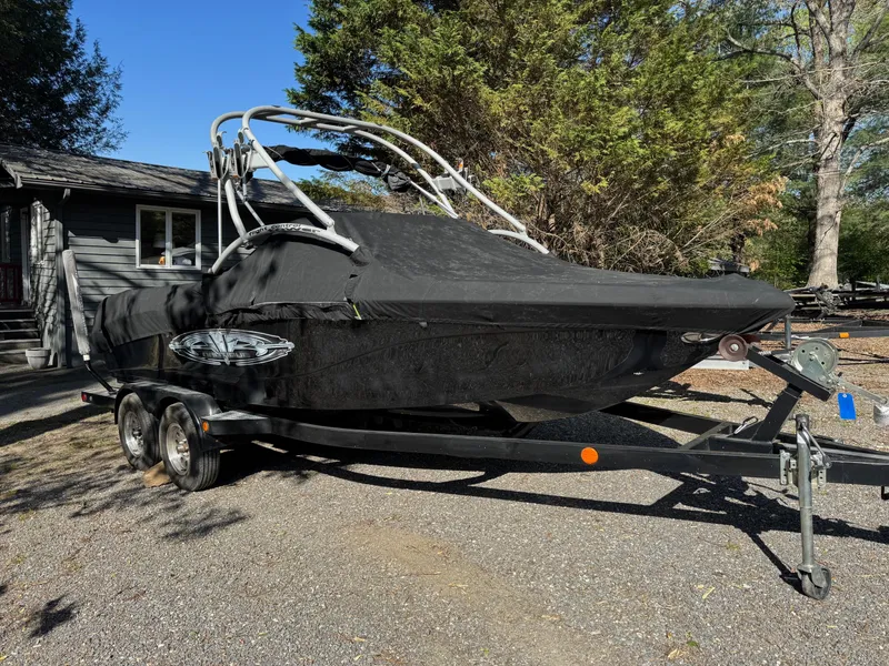 Slide: The Image of 2004 Correct Craft AIR NAUTIQUE SV 211 boat with cover on trailer, parked outdoors. - 14