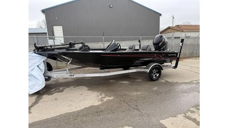 Slide: The Image of 2025 Xpress H18 boat on trailer, black exterior, parked outdoors. - 1