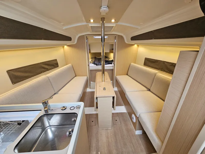 Slide: The Image of Interior of 2022 Beneteau Oceanis 30.1 yacht, featuring modern seating and compact kitchen area. - 10