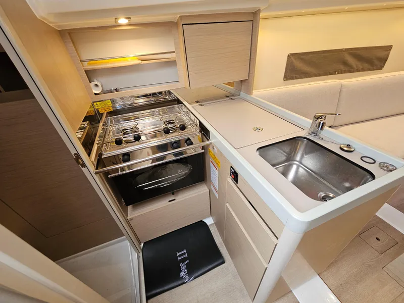 Slide: The Image of Modern kitchen in 2022 Beneteau Oceanis 30.1 yacht with stove, sink, and storage. - 11