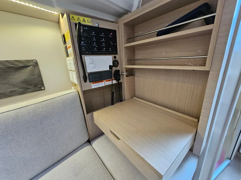 Slide: The Image of Interior of 2022 Beneteau Oceanis 30.1 yacht with control panel and wooden shelves. - 14