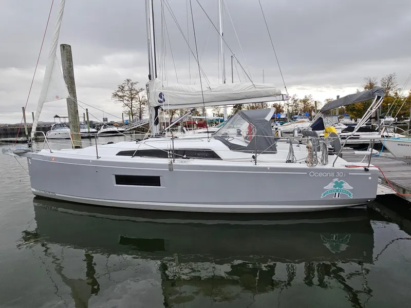 Slide: The Image of 2022 Beneteau Oceanis 30.1 sailboat docked in a marina under cloudy skies. - 2