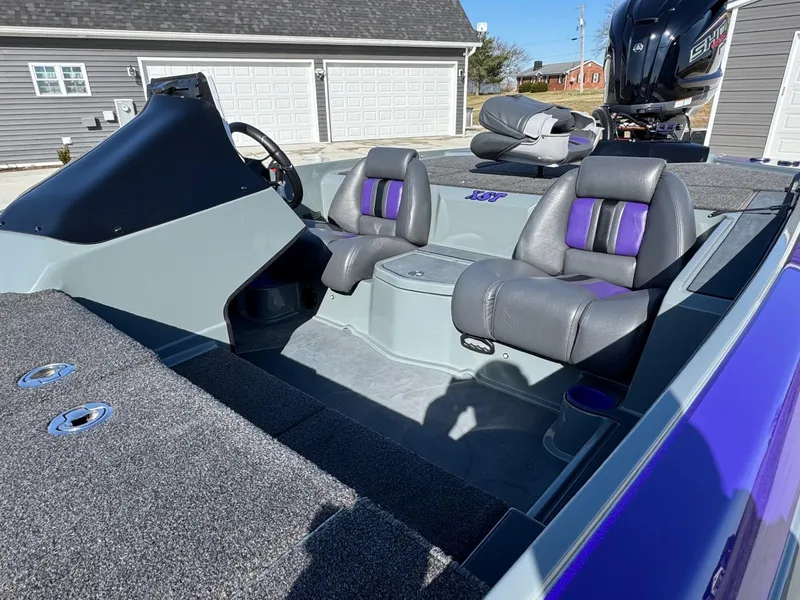 Slide: The Image of 2025 Bullet 21XST boat interior with gray and purple seats, parked in a driveway. - 11