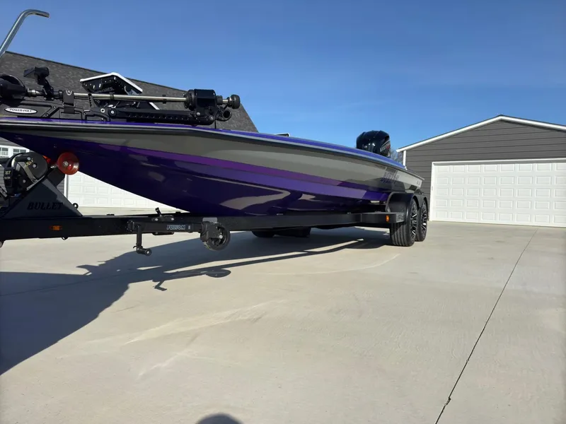 Slide: The Image of 2025 Bullet 21XST boat on trailer in driveway, featuring sleek purple and black design. - 4
