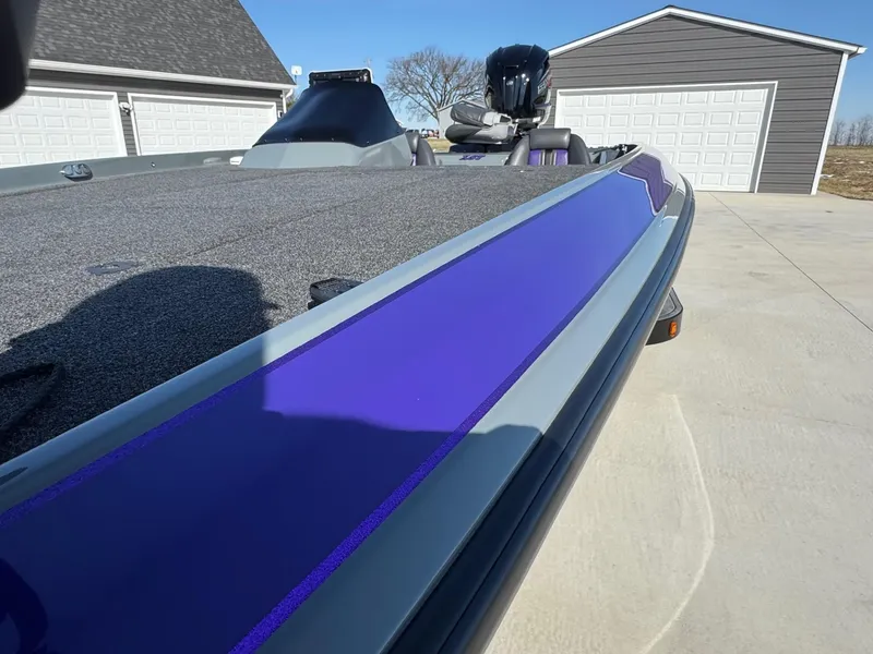 Slide: The Image of 2025 Bullet 21XST boat with purple detailing, parked near a garage. - 5