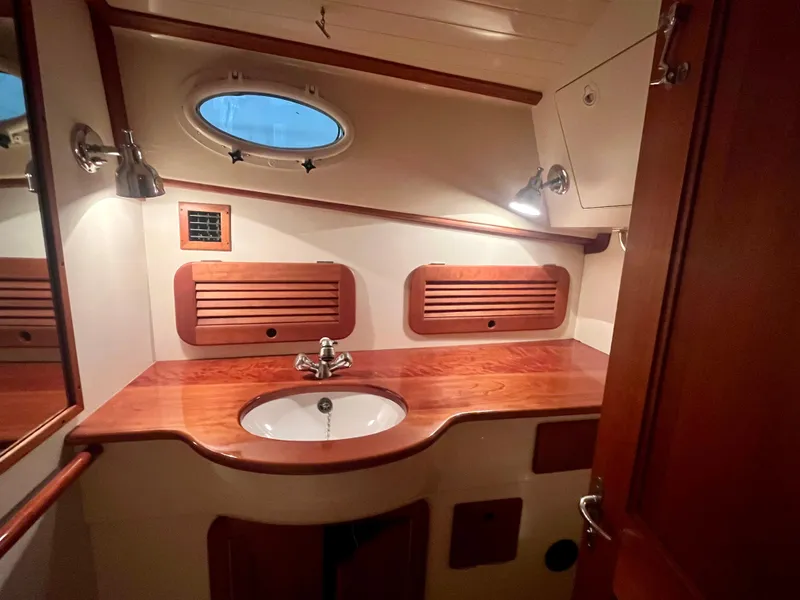 Slide: The Image of 2005 Hinckley Picnic Boat EP bathroom with wooden cabinetry and oval porthole window. - 11