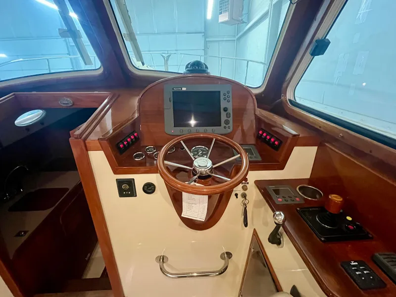 Slide: The Image of 2005 Hinckley Picnic Boat EP helm with wooden steering wheel and navigation controls. - 12