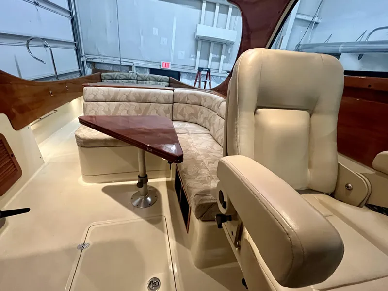 Slide: The Image of 2005 Hinckley Picnic Boat EP interior with beige seating and wooden table. - 15
