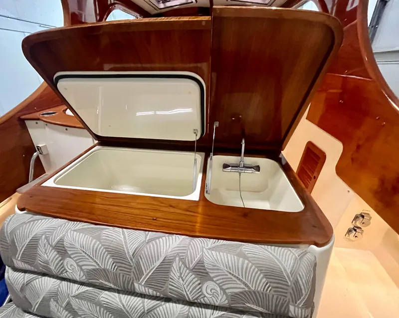 Slide: The Image of 2005 Hinckley Picnic Boat EP interior with open storage and sink, featuring elegant wood finish. - 16