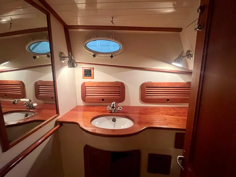 Slide: The Image of 2005 Hinckley Picnic Boat EP bathroom with wooden accents and porthole window. - 19