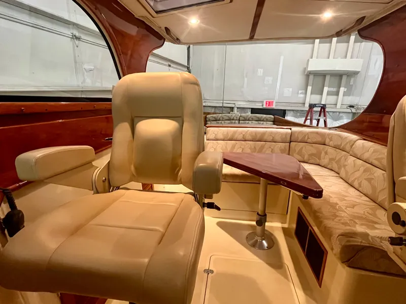 Slide: The Image of 2005 Hinckley Picnic Boat EP interior with beige seating and wooden table. - 3