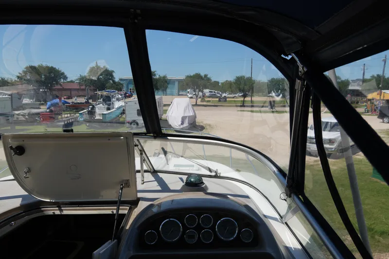 Slide: The Image of 2003 Bayliner Ciera 2855 cockpit view with dashboard and outdoor marina scene. - 13